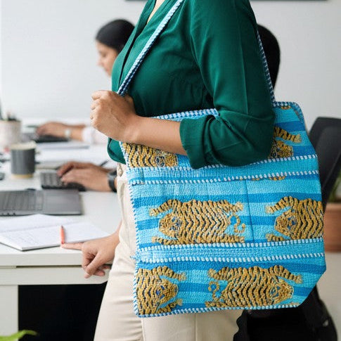Woman holding this junglee blue and gold patterned tote bag in an office